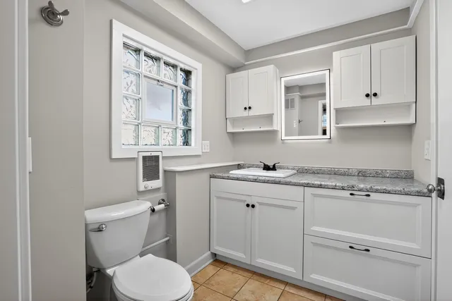 a bathroom with a granite countertop toilet sink and window