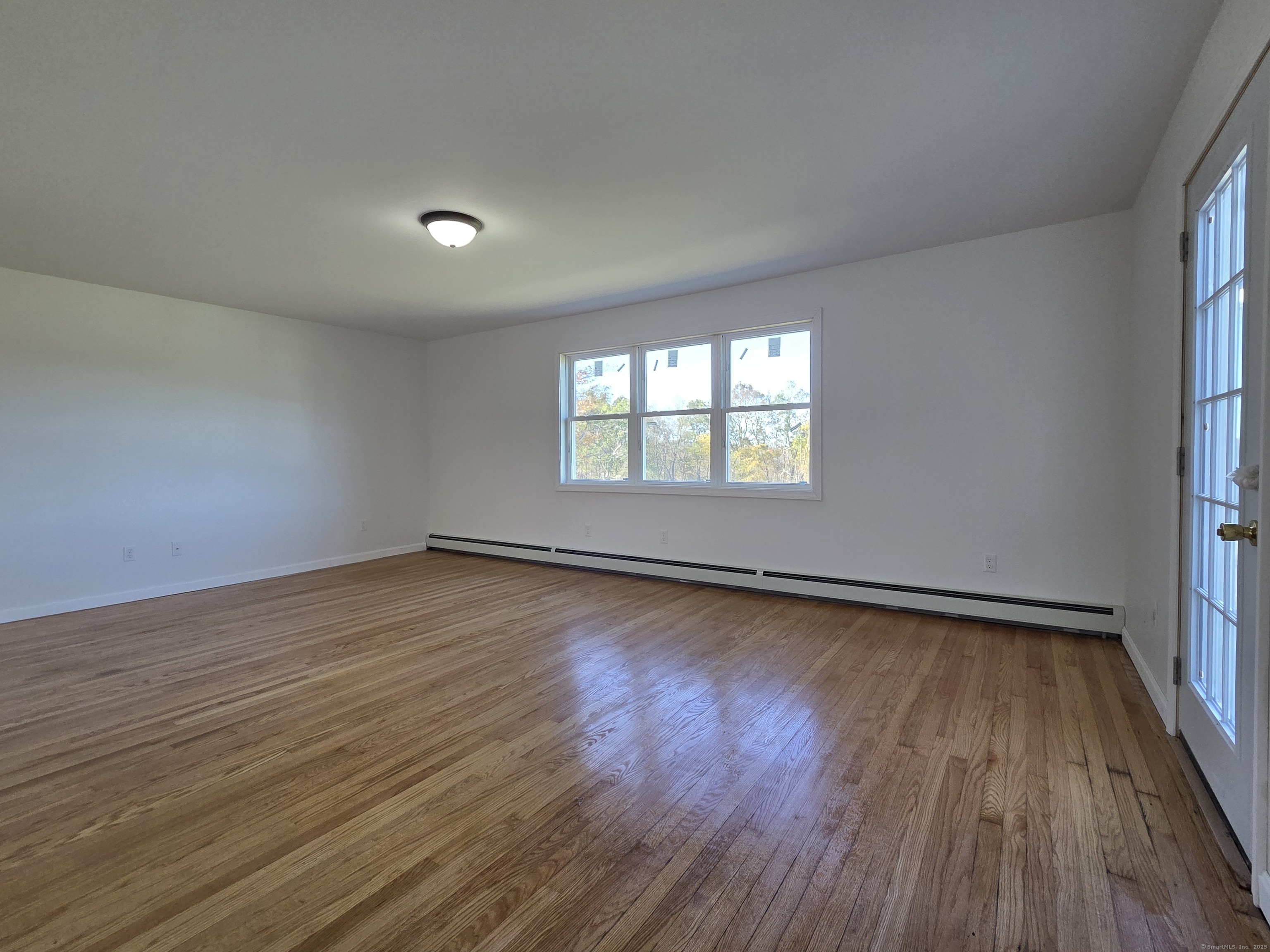 395 Bailey Hill Road Killingly, CT 06239 - Photo 13 of 36 an empty room with wooden floor and windows
