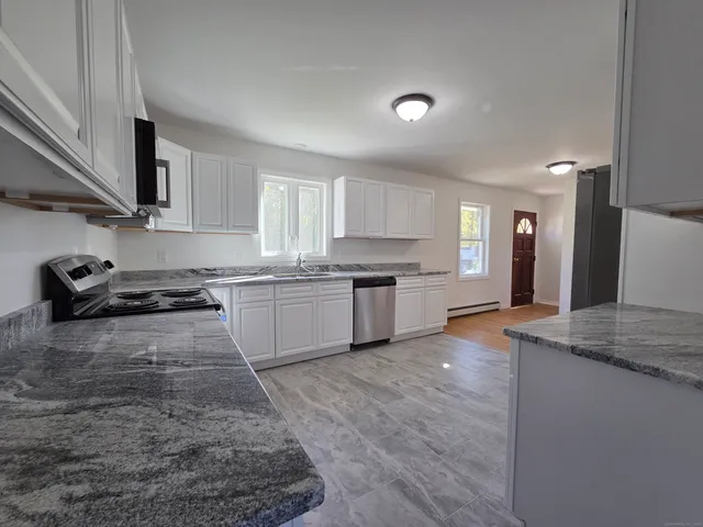a large kitchen with stainless steel appliances granite countertop a stove a sink dishwasher and a refrigerator