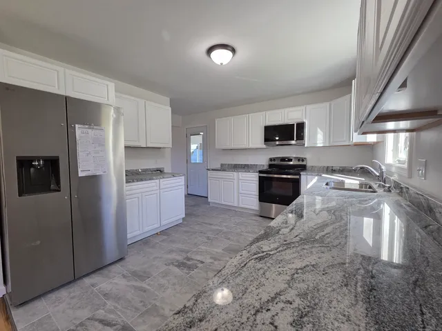 a kitchen with granite countertop a refrigerator and a sink