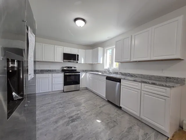 a kitchen with granite countertop white cabinets and stainless steel appliances