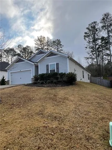 a front view of house with yard and trees in the background
