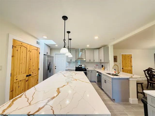 a large kitchen with kitchen island a sink stainless steel appliances and cabinets