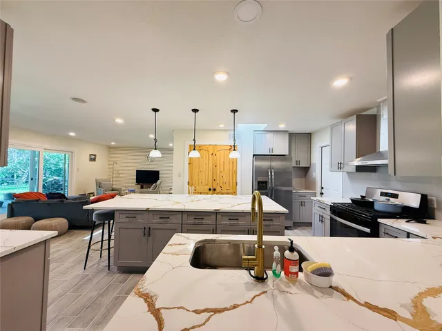 a kitchen with kitchen island granite countertop a sink counter top space appliances and cabinets