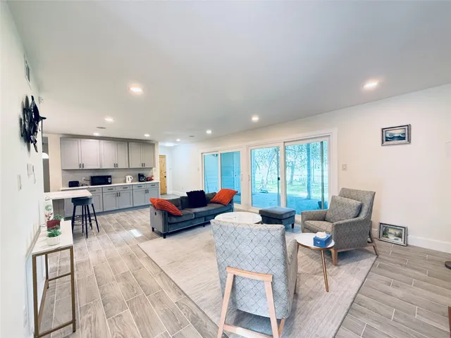a living room with furniture kitchen view and a window