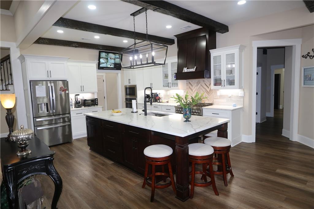 3251 Lenora Church Road Snellville, GA 30039 - Photo 10 of 48 a kitchen with stainless steel appliances a dining table chairs and wooden floor