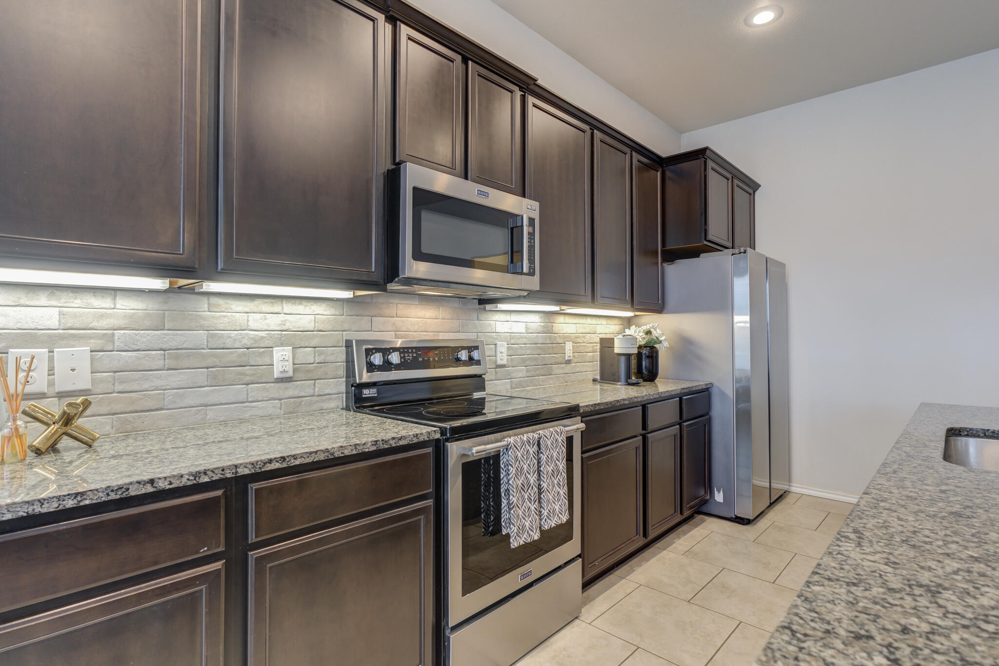 7201 94th Street Lubbock, TX 79424 - Photo 12 of 34 a kitchen with stainless steel appliances granite countertop wooden cabinets a stove top oven a sink and dishwasher