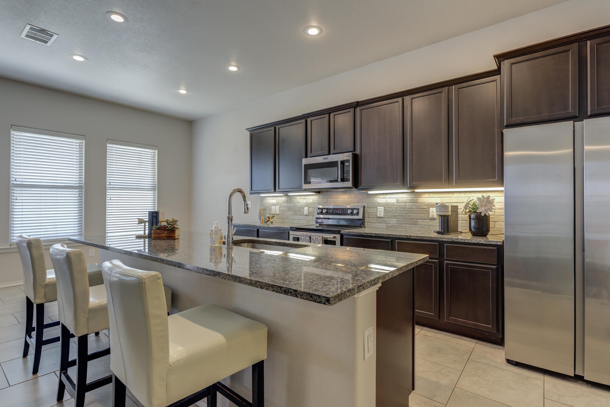 7201 94th Street Lubbock, TX 79424 - Photo 17 of 34 a kitchen with kitchen island granite countertop a sink stove and refrigerator