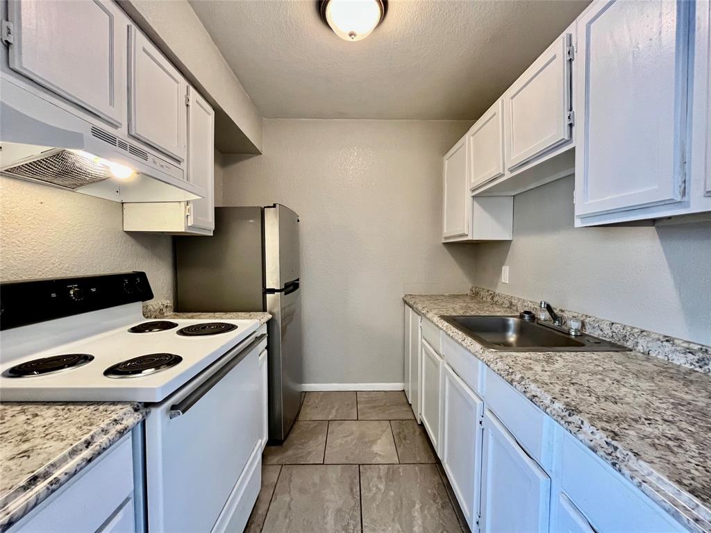701 West Sycamore Street, Unit 203 Denton, TX 76201 - Photo 5 of 10 a kitchen with stainless steel appliances granite countertop a sink stove and refrigerator