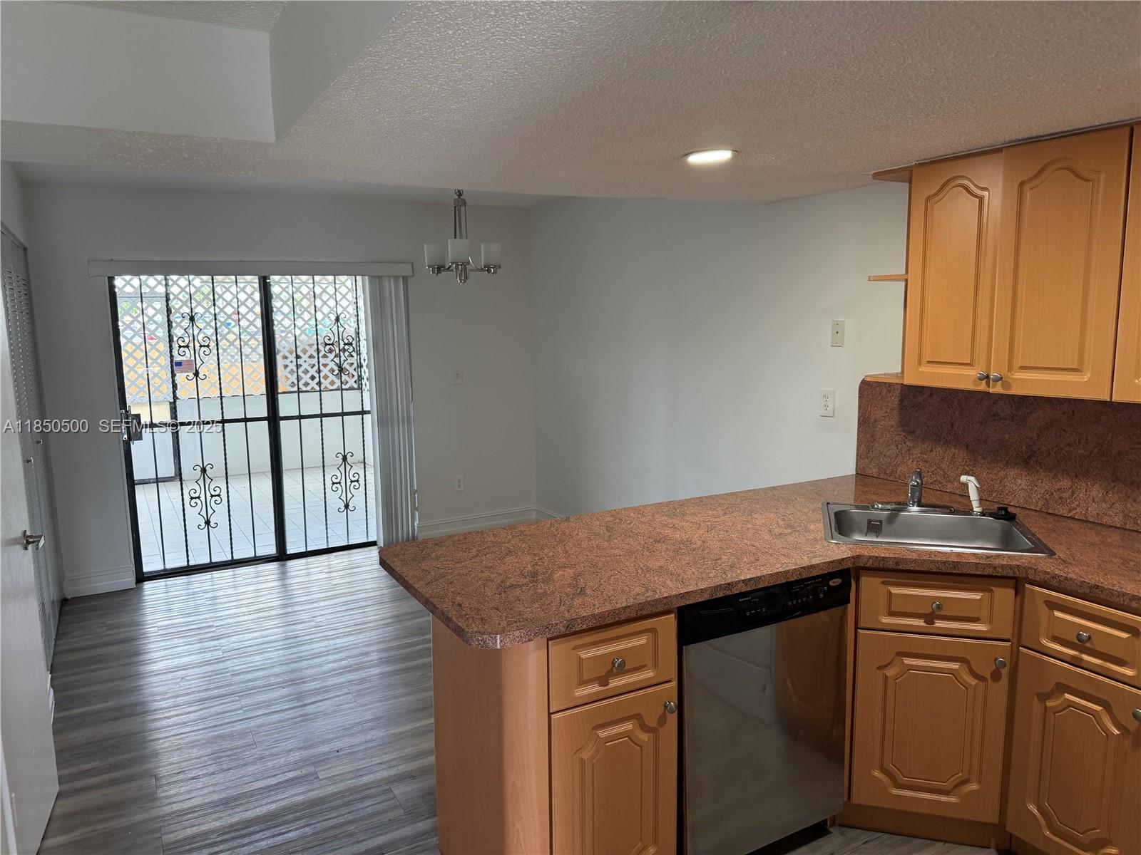 2289 West 52nd Street, Unit 23 Hialeah, FL 33016 - Photo 9 of 23 a kitchen with granite countertop a sink a stove cabinets and wooden floor