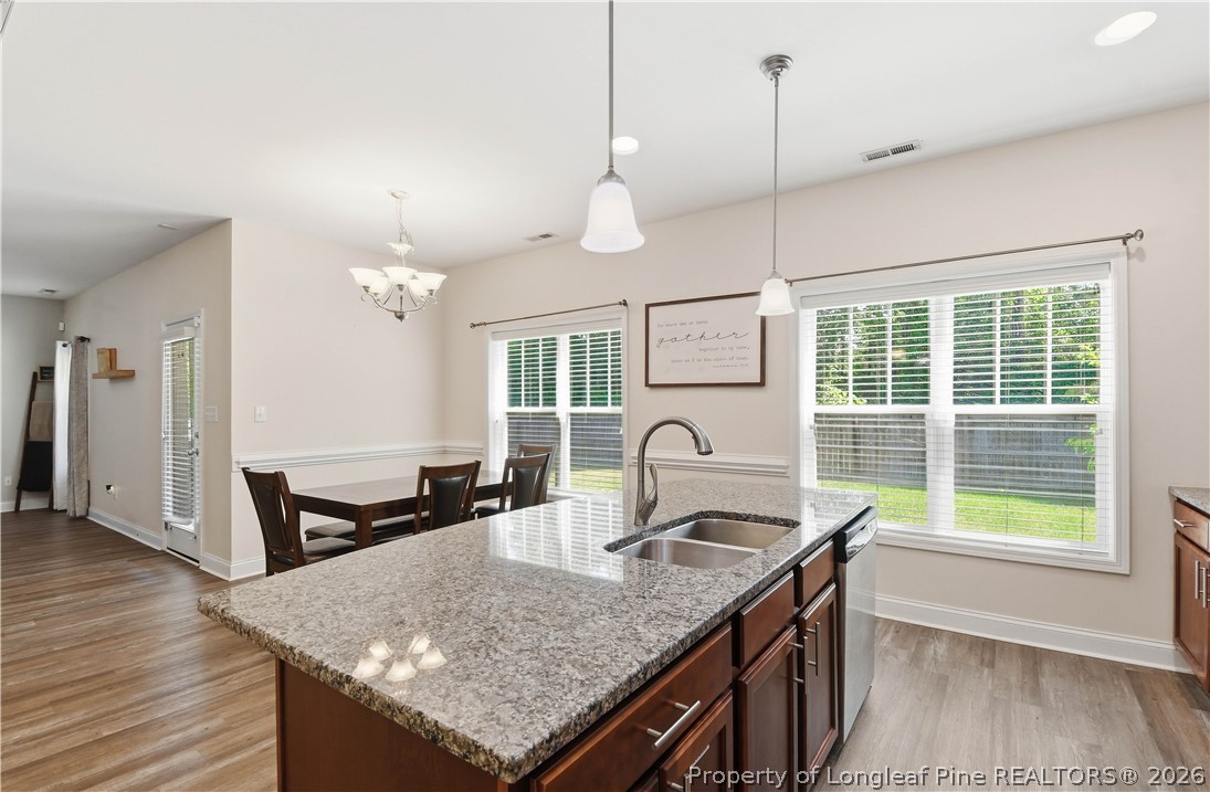 140 Birch Avenue Spring Lake, NC 28390 - Photo 25 of 49 a kitchen with a kitchen island a stove a sink a dining table and chairs with wooden floor