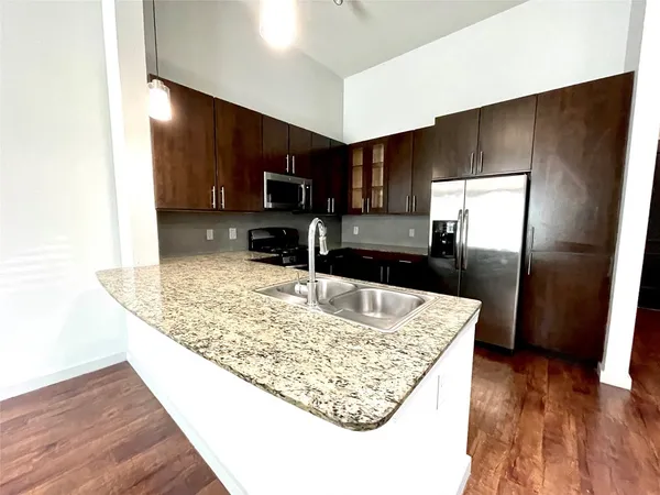 a kitchen with stainless steel appliances granite countertop a sink refrigerator and microwave