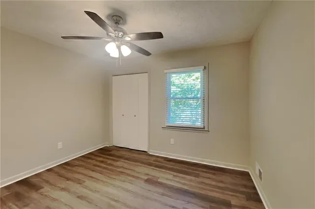 an empty room with wooden floor fan and windows