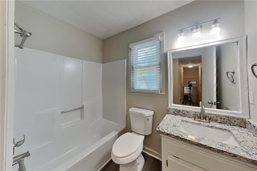 3117 Calumet Circle Northwest Kennesaw, GA 30152 - Photo 17 of 21 a bathroom with a granite countertop sink toilet a large mirror a bathtub and shower