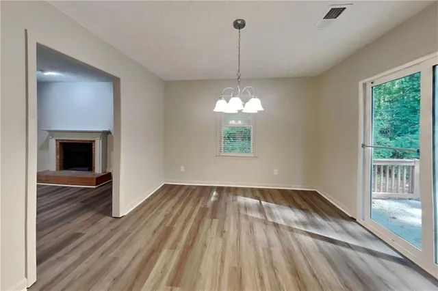 a view of an empty room with wooden floor kitchen view and a window