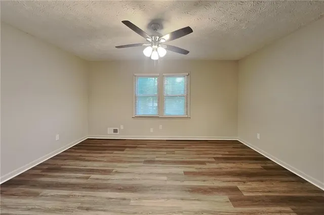a view of an empty room with window and chandelier fan