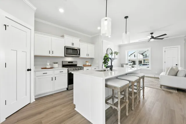 a kitchen with stainless steel appliances granite countertop a stove top oven a sink a dining table and chairs with wooden floor