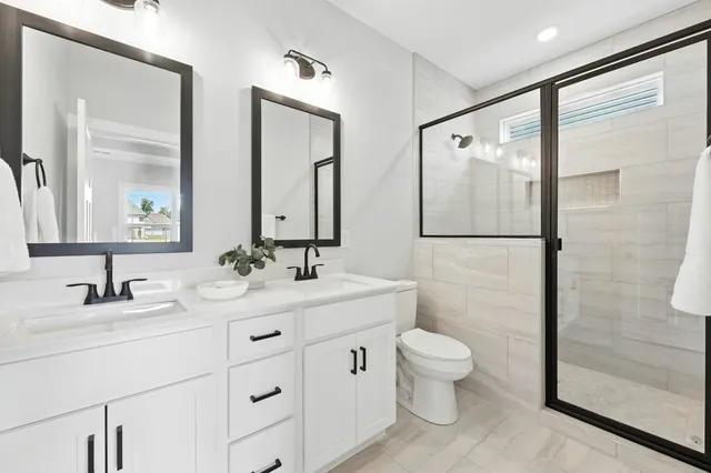 a bathroom with a double vanity sink toilet mirror and shower