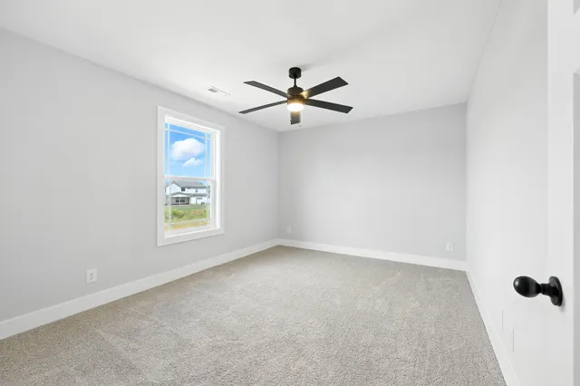 an empty room with windows and fan