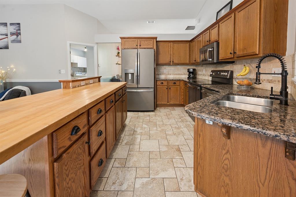 6924 Southwest 80th Drive Gainesville, FL 32608 - Photo 23 of 65 a kitchen with stainless steel appliances granite countertop a sink a stove top oven a chimney cabinets and a counter top space