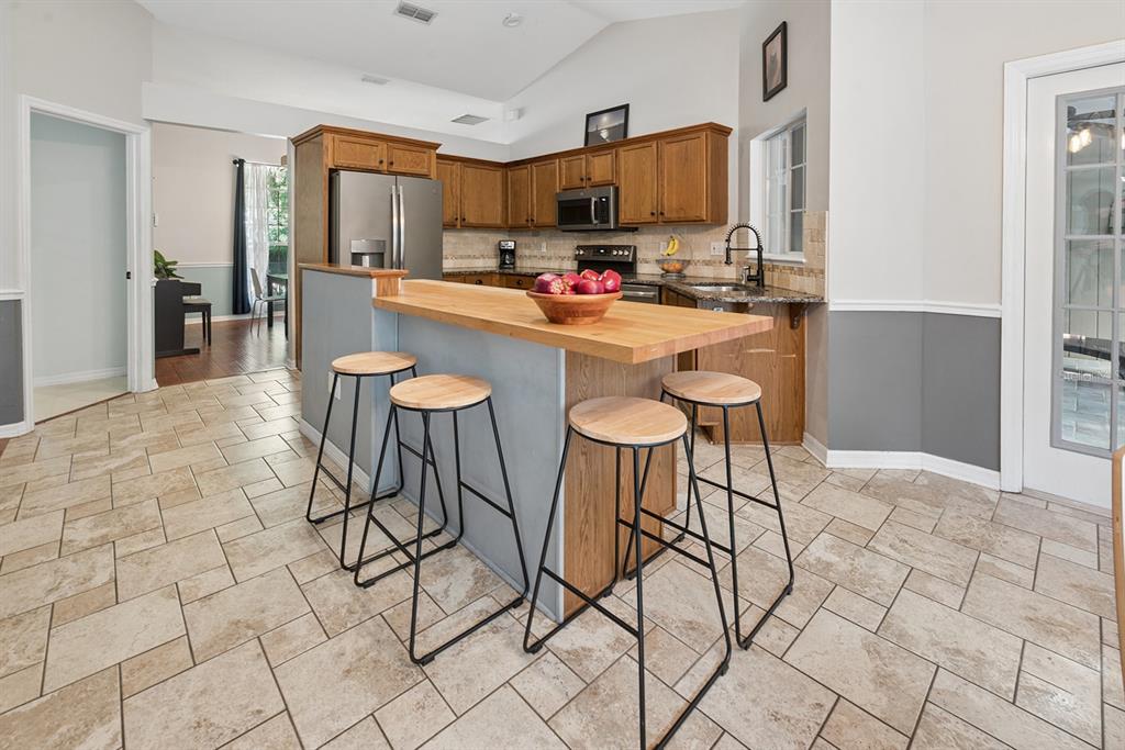 6924 Southwest 80th Drive Gainesville, FL 32608 - Photo 25 of 65 a kitchen with stainless steel appliances granite countertop a stove a sink a dining table and chairs