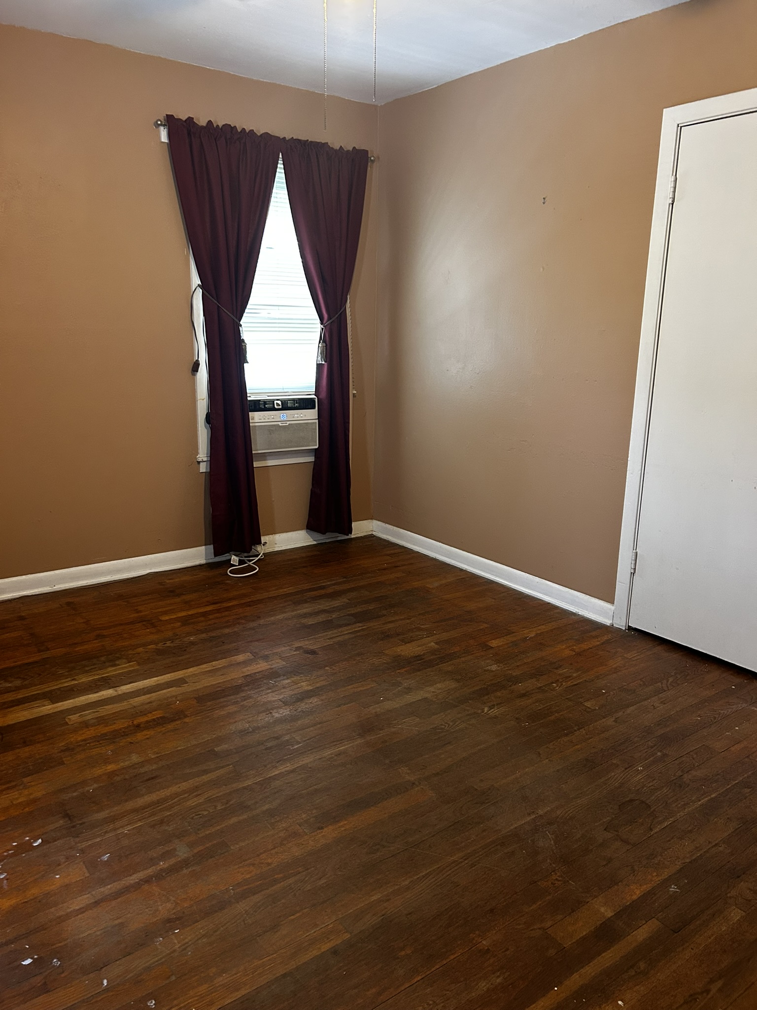 5702 Duval Street Austin, TX 78752 - Photo 24 of 31 Room featuring wood-finish flooring, a window with an integrated air conditioning unit, and a white interior door