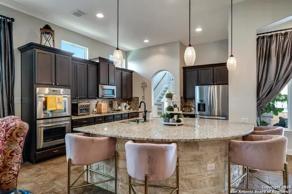 a kitchen with granite countertop a table chairs microwave and sink