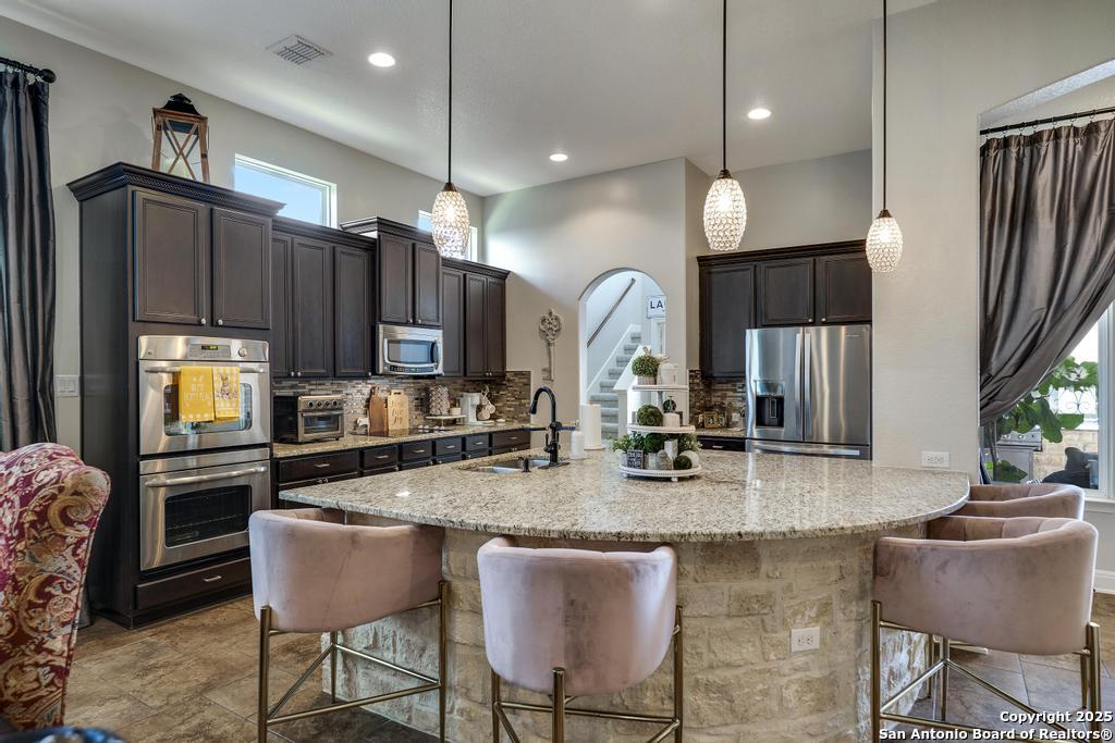 13326 Windmill Trace Helotes, TX 78023 - Photo 11 of 34 a kitchen with granite countertop a table chairs microwave and sink