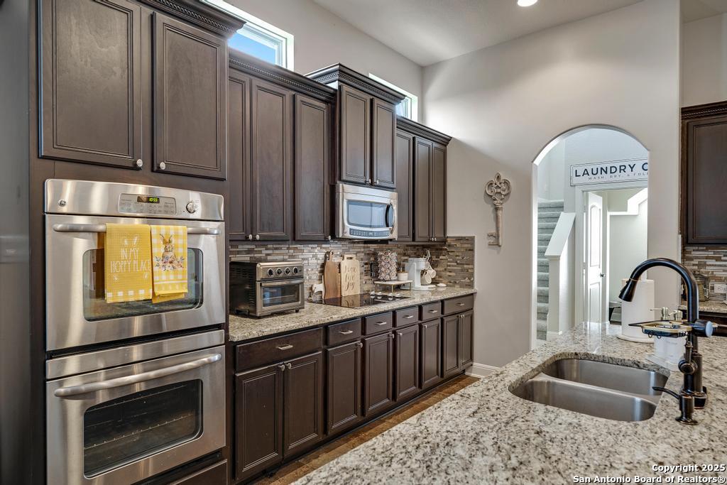 13326 Windmill Trace Helotes, TX 78023 - Photo 12 of 34 a kitchen with stainless steel appliances granite countertop a sink stove and refrigerator