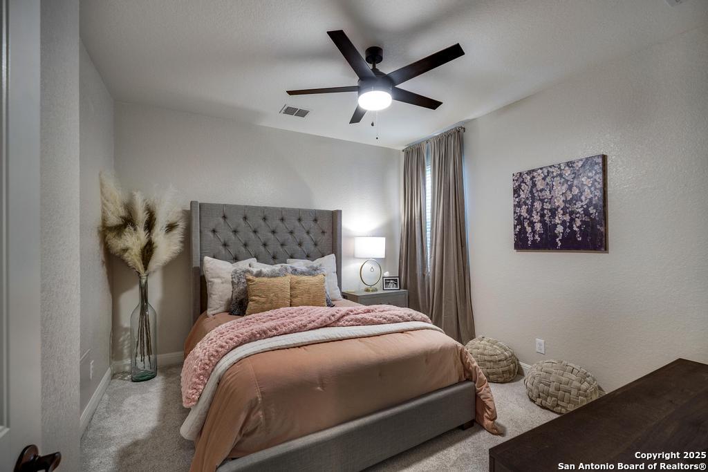 13326 Windmill Trace Helotes, TX 78023 - Photo 20 of 34 a bedroom with a large bed and a chandelier