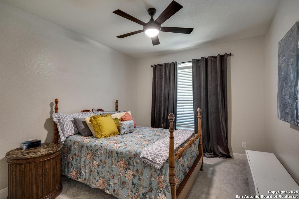 13326 Windmill Trace Helotes, TX 78023 - Photo 22 of 34 a bedroom with a bed and a chandelier