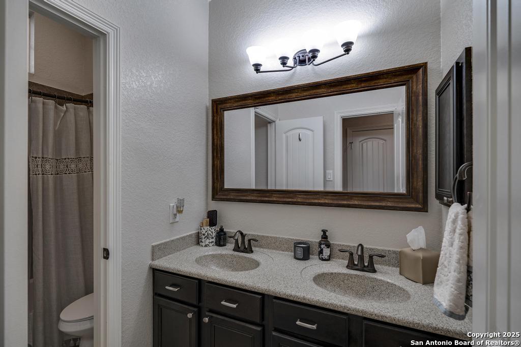 13326 Windmill Trace Helotes, TX 78023 - Photo 23 of 34 a bathroom with a toilet sink and mirror