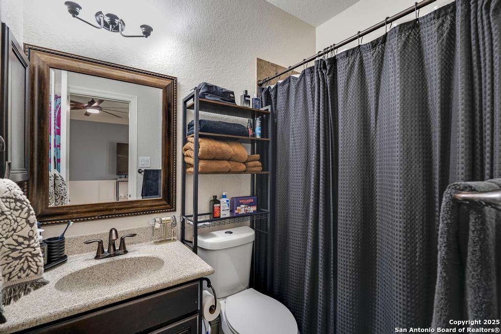 13326 Windmill Trace Helotes, TX 78023 - Photo 28 of 34 a bathroom with sink a mirror a toilet and shower