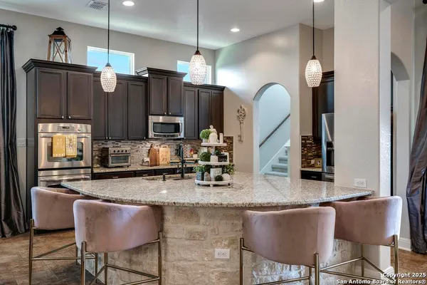 a kitchen with granite countertop kitchen island stainless steel appliances a refrigerator a stove a sink cabinets and a dining table