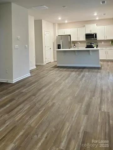 a large kitchen with stainless steel appliances kitchen island granite countertop a large counter top and wooden floors