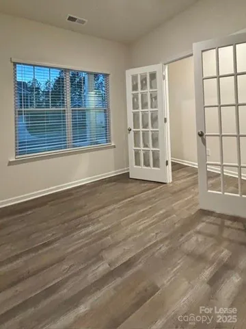 an empty room with wooden floor and windows