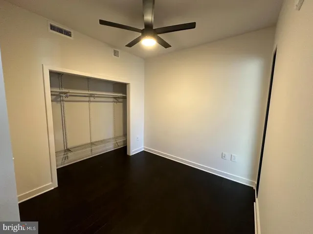 an empty room with wooden floor and fan