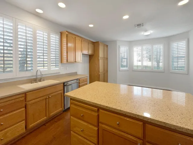 a large kitchen with kitchen island granite countertop a sink and dishwasher wooden cabinets with a large window