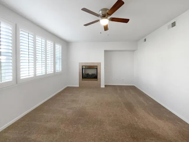 an empty room with a ceiling fan and a window