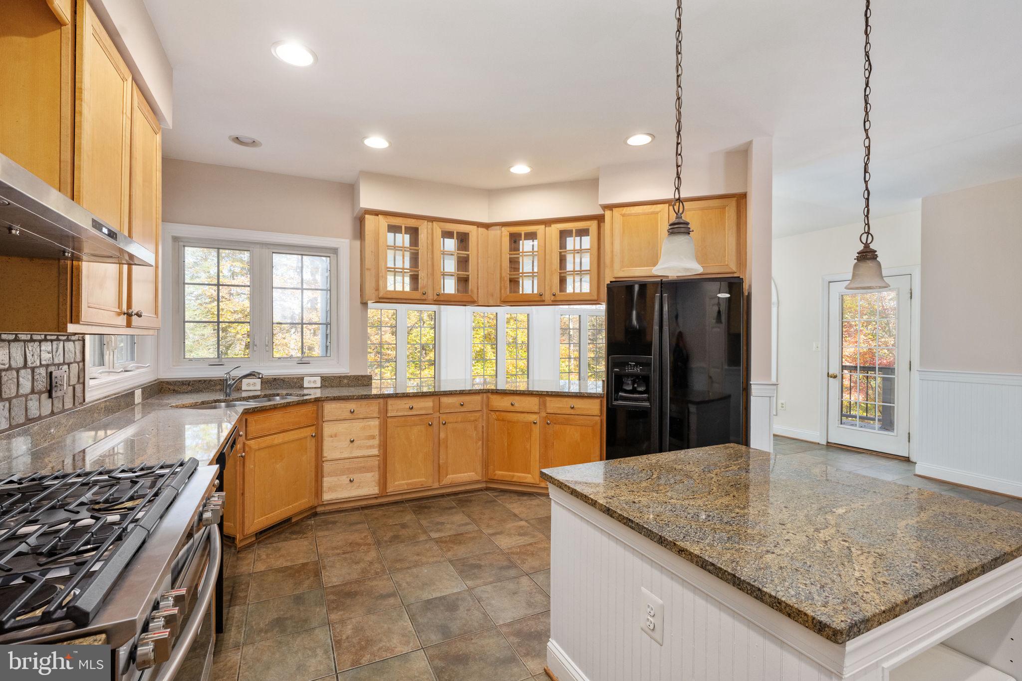231 Kimberwick Lane Stafford, VA 22556 - Photo 26 of 78 a large kitchen with granite countertop a stove a sink a refrigerator and blue cabinets with wooden floor