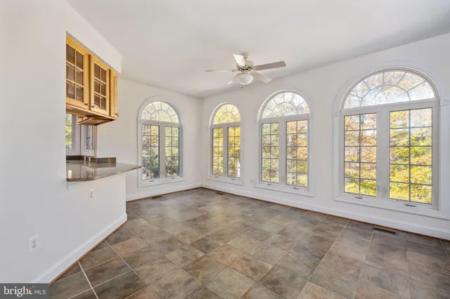 an empty room with windows and ceiling fan