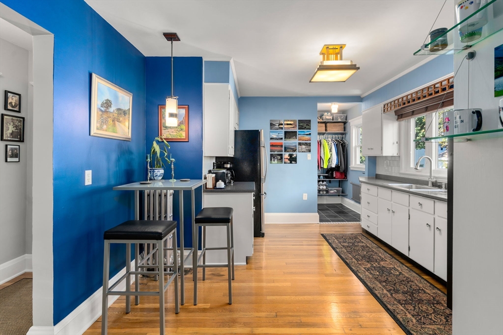 15 Berkshire Road, Unit 1 Waltham, MA 02453 - Photo 19 of 42 a kitchen with stainless steel appliances kitchen island granite countertop a refrigerator a stove and a dining table with wooden floor