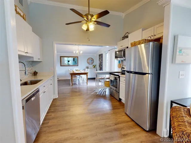 a kitchen with stainless steel appliances a refrigerator a stove a sink a dining table and chairs with wooden floor