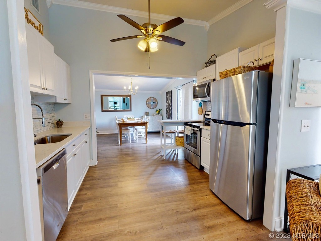 69 Sabal Cay Court, Unit 690 New Smyrna Beach, FL 32169 - Photo 5 of 30 a kitchen with stainless steel appliances a refrigerator a stove a sink a dining table and chairs with wooden floor