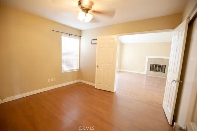 an empty room with wooden floor and ceiling fan