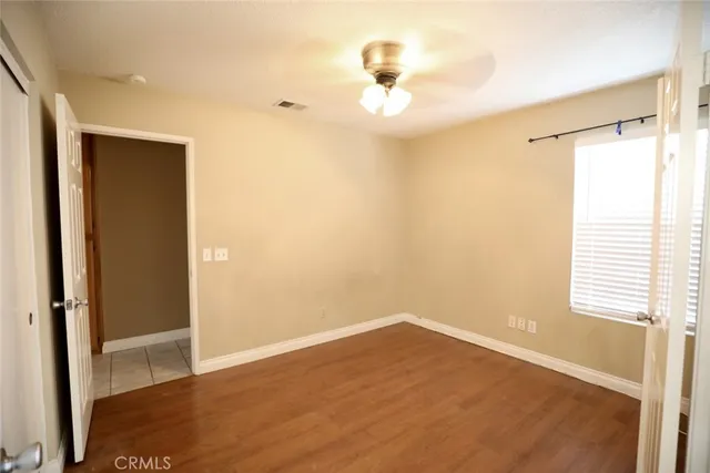 a view of empty room with wooden floor and fan