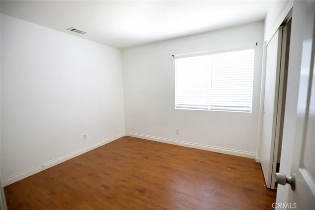 an empty room with wooden floor and window