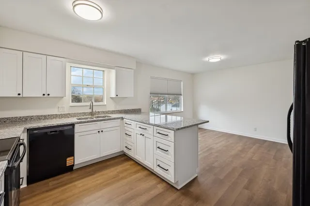 a kitchen with stainless steel appliances granite countertop a stove a sink and white cabinets