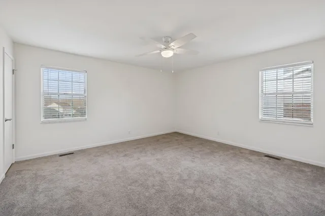 an empty room with a window and ceiling fan
