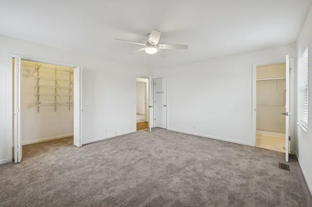 an empty room with closet and a ceiling fan